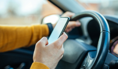 Person driving carelessly using mobile phone behind the wheel